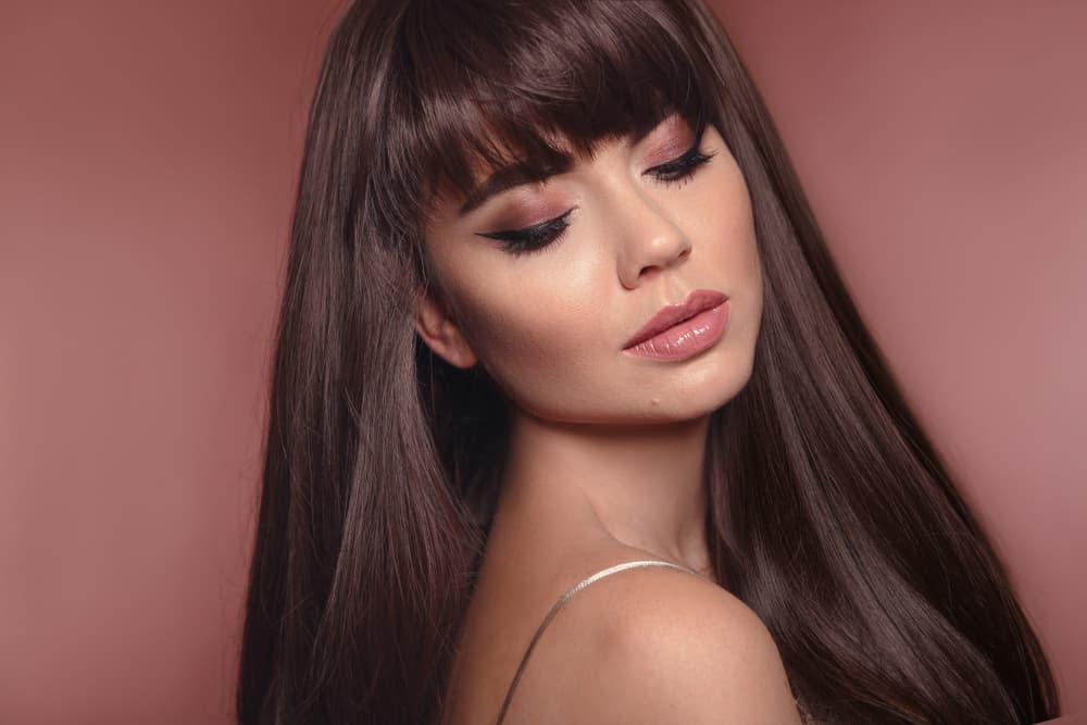 Woman with glossy brunette hair and fringe, styled smooth and shiny after autumn colour refresh at Honeys Hair & Beauty Taunton